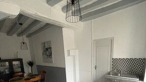 Une cuisine moderne avec un parquet en chevrons, un coin repas avec une table et des chaises en bois, et une suspension au-dessus de la table.