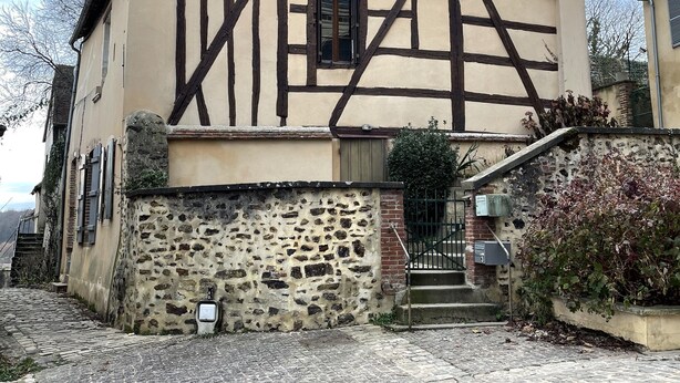 Une maison traditionnelle à colombages, avec des fondations en pierre, un toit en tuiles et une petite fenêtre.