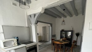 Une cuisine compacte dotée d’appareils électroménagers modernes, un coin repas avec des chaises en bois et un plancher à motifs en chevrons.