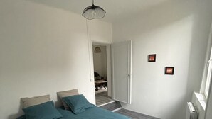 Une chambre à coucher avec un lit, une porte, un radiateur et un luminaire suspendu.