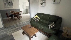 Un salon avec un canapé vert, une table basse en bois et un luminaire suspendu.