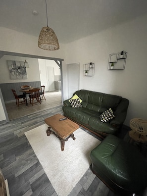 Una sala de estar con un sofá verde, una mesa de centro de madera y una lámpara colgante.
