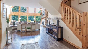 Ein geräumiger Wohnbereich mit einer Holztreppe, einem großen Fenster und einem Kamin.