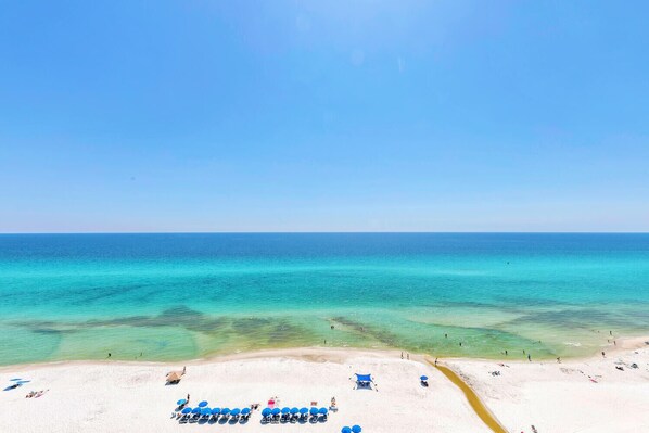 Relax on the beach with comfortable sun loungers and umbrellas, surrounded by turquoise waters and a sandy shore.