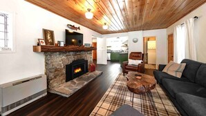 A cozy living room with a stone fireplace, wooden ceiling, and a modern sofa.
