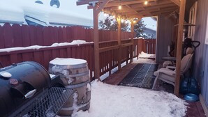 Un espacio al aire libre cubierto con una parrilla, un barril metálico y una terraza de madera.