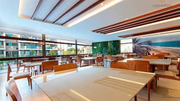 Un restaurante moderno con mobiliario de madera, ventanas amplias y vista al océano.