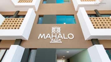 Un edificio con un llamativo letrero que dice 'MAHALO' y un diseño arquitectónico moderno.