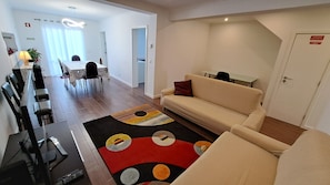 Een moderne woonkamer met een bank, een eettafel met stoelen en een keukenhoek.