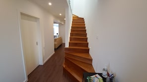 Een trap die leidt naar de tweede verdieping in een modern appartement met houten vloeren en witte muren.