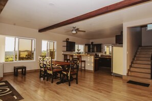 Enjoy meals with family and friends in this open-plan living area featuring a dining table for four and a staircase leading to an upper level.