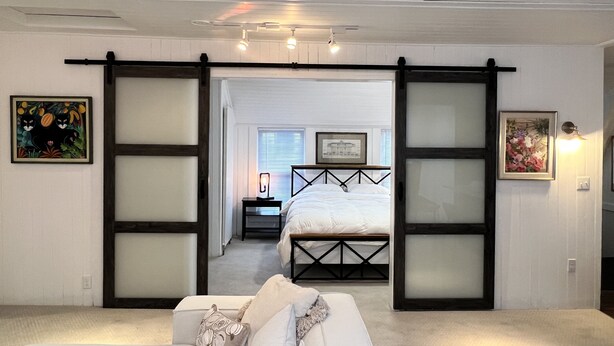 Un dormitorio con cama, sofá y puerta corredera que da a otra habitación.