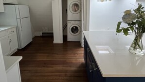 Cocina compacta con lavadora, suelo de madera y luces colgantes.