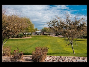 A well-maintained lawn with a gazebo, a stone wall, and a clear sky.
