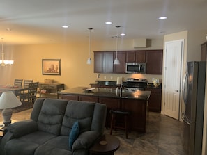 A modern kitchen with dark wooden cabinets, stainless steel appliances, and a central island.
