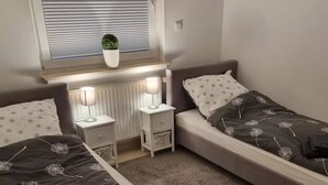 Makuuhuoneessa on kaksi erillistä sänkyä, pieni pöytä, kaksi yöpöytävalaisinta, patteri ja ikkuna, jossa on sälekaihtimet.