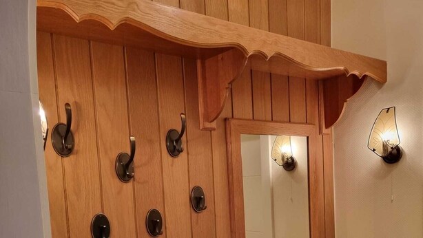 Puinen seinä, jossa on peili ja seinälle kiinnitetyt koukut.