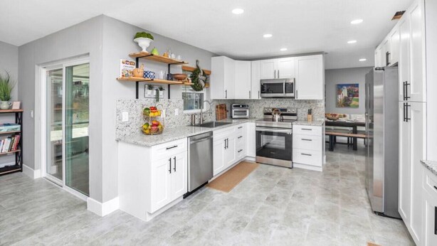 A modern kitchen with white cabinetry, granite countertops, and stainless steel appliances.