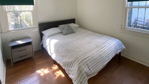 A bedroom with a bed, a nightstand, a window with a green valance, and a ceiling light.