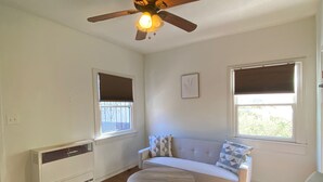 A living room with a ceiling fan, a sofa, a round coffee table, and a chair.
