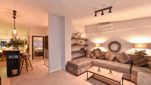 A modern living room with a sectional sofa, a coffee table, and a fireplace. There is a kitchen visible in the background. - Penthouse Lake Mountains View Incl Summer Card (Zell am See)