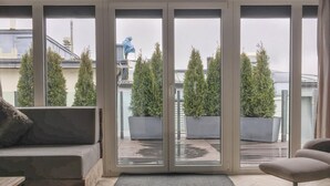 A modern living room with a sofa, a chair, and a large sliding glass door leading to a balcony with potted plants. - Penthouse Lake Mountains View Incl Summer Card (Zell am See)