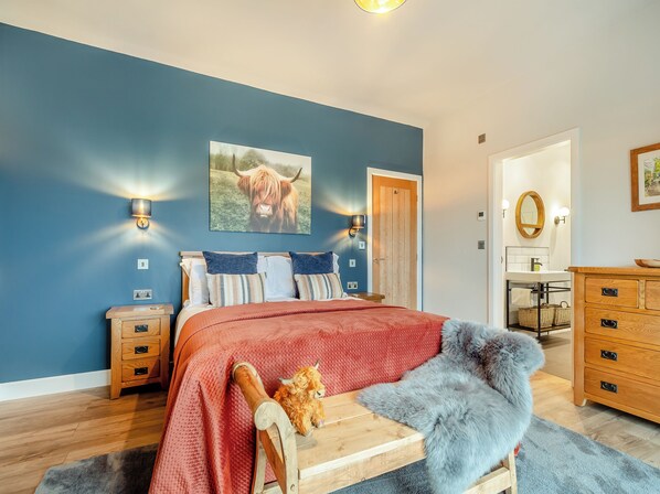 Ein Schlafzimmer mit Bett, Nachttischen, Kommode, Spiegel und Tür.