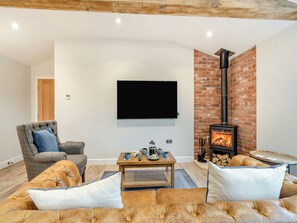 A living room with a flat-screen TV, a brick fireplace, a comfortable sofa, and a coffee table. - The Workshop - UK42470 (Pickering)