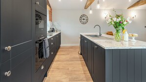 A modern kitchen with dark cabinetry, a marble countertop, and pendant lighting. - The Workshop - UK42470 (Pickering)