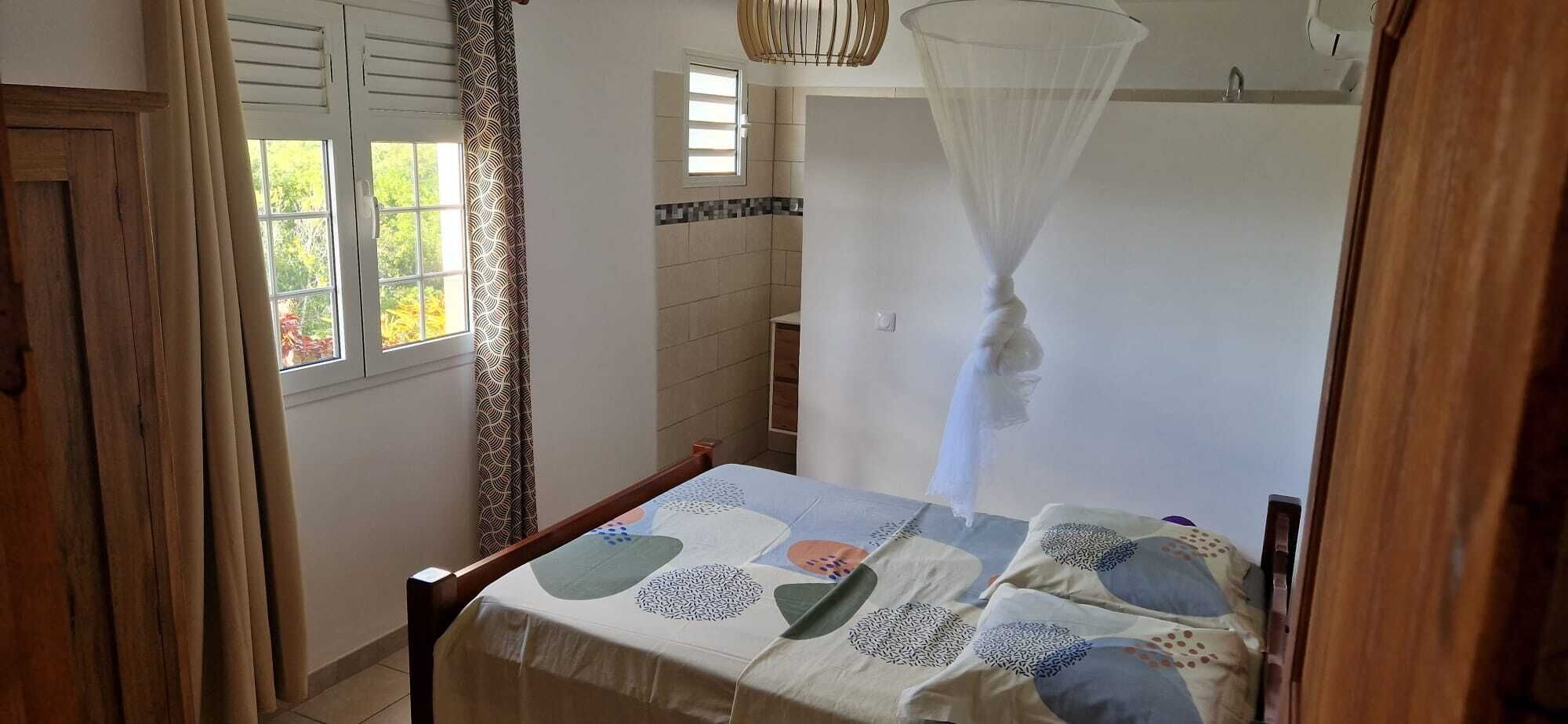 A bedroom with a bed, a window, a door, and a mosquito net.
