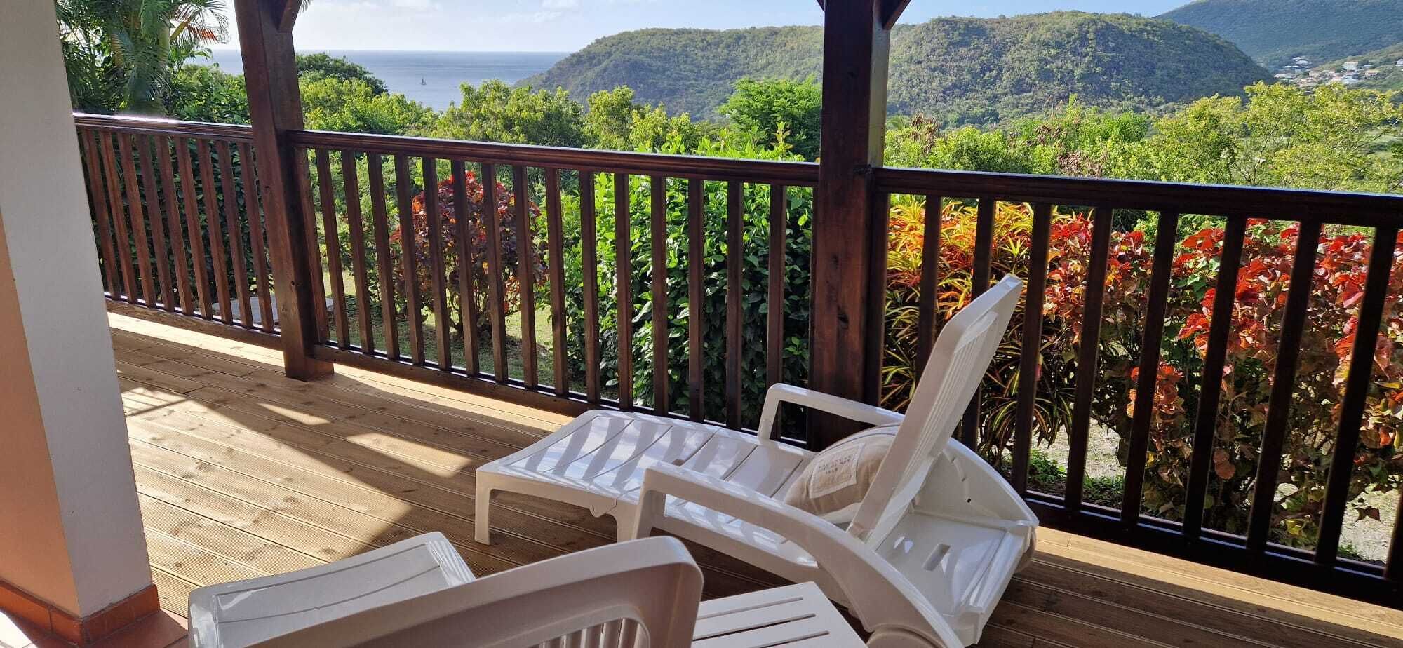 Eine Holterrasse mit weißen Plastikstühlen und Blick auf eine Berglandschaft.