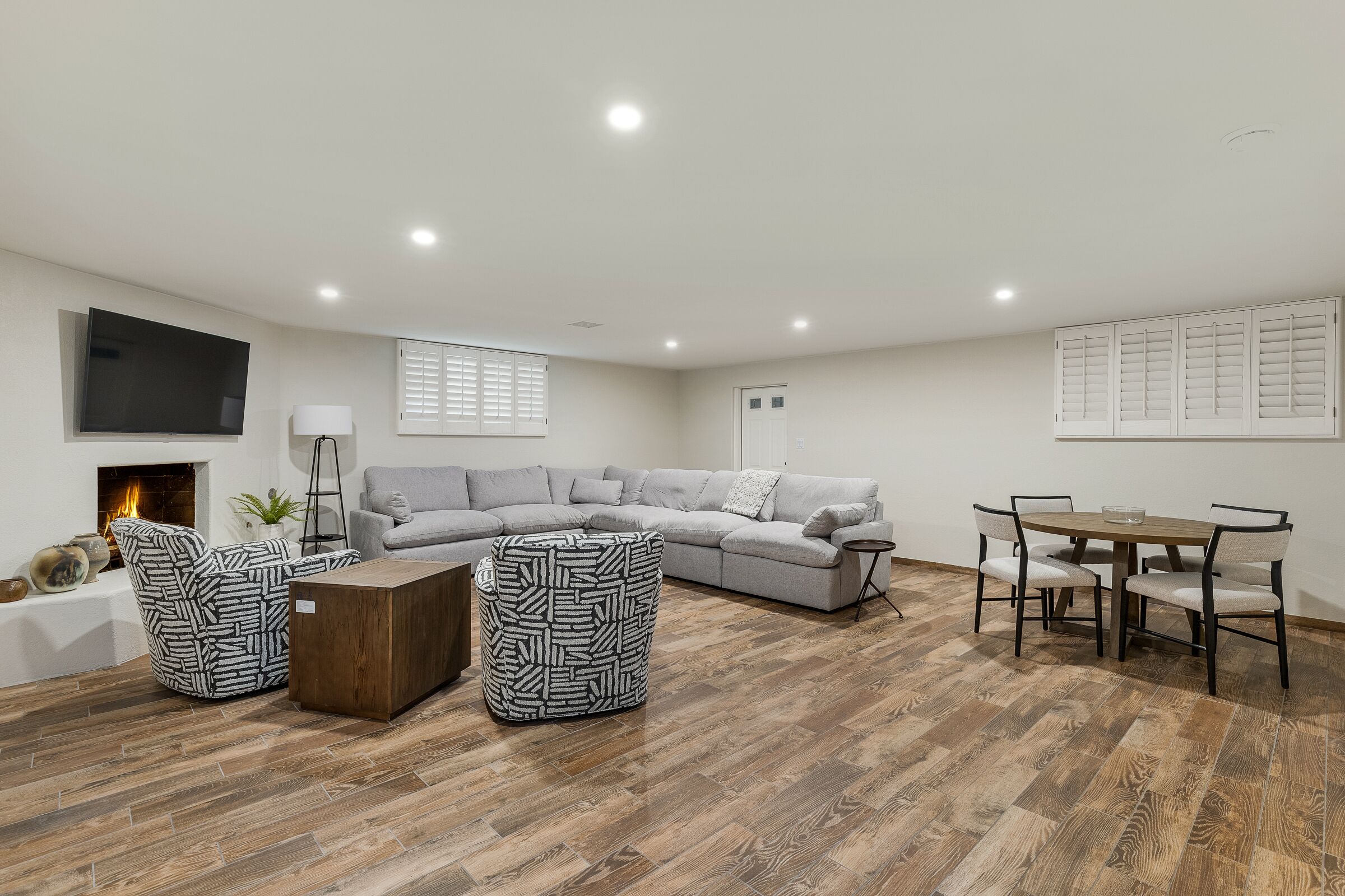 A modern living room with a sectional sofa, a wooden coffee table, and a dining table with chairs.