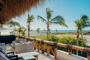Relax in a serene outdoor space with ocean views, wicker furniture, and a thatched roof.