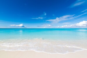 A beach with clear turquoise water and a sandy shore. - The Blu2 On the Beach, Luxury Oceanfront Penthouse Condo at the Grandview (Grace bay)