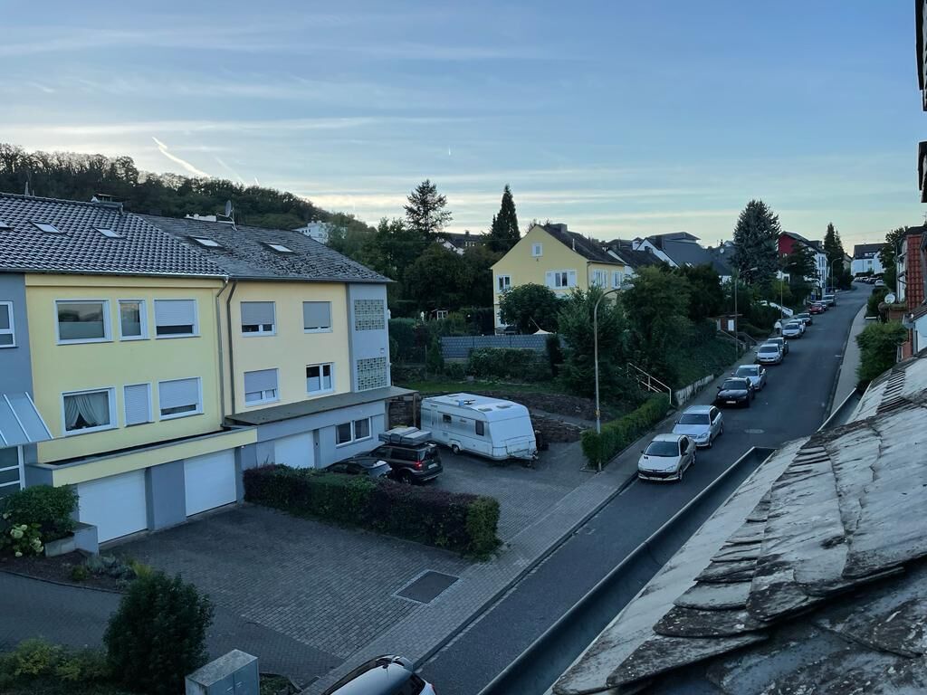 Une rue résidentielle bordée de maisons, avec des voitures garées et un fourgon.