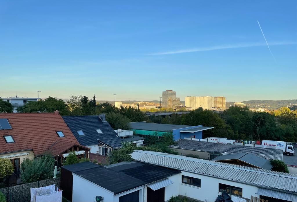 Ein Wohngebiet mit Häusern, einige mit Solaranlagen, und im Hintergrund hohe Gebäude.
