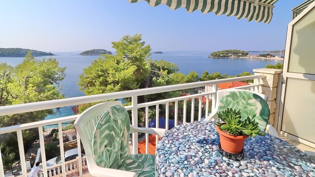 Ein Balkon mit Meerblick, einem Blumentopf und einem Tisch mit Mosaikplatte.
