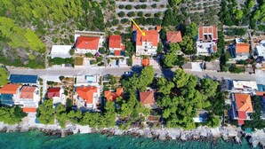 Eine Luftaufnahme einer Küstenwohngegend mit Häusern, einer Straße und freiem Blick auf das Meer.