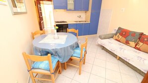 Ein kleiner Wohnbereich mit Esstisch, Stühlen, einer Couch und einer Küchenzeile.