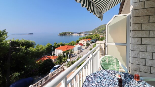 Ein Balkon mit Meerblick, ein Tisch mit Flasche und Glas sowie ein Stuhl.