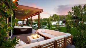 Une terrasse extérieure avec un foyer, un espace salon et un jacuzzi.