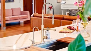 Une cuisine moderne dotée d’un plan de travail en marbre, d’un évier et d’un coin repas avec un piano.
