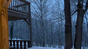 A wooden deck with a railing, surrounded by snow-covered ground and trees. - Ski in/out Condo Modern Mountain Top at Snowriver Resort (Wakefield)