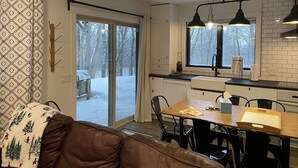 A modern kitchen with a dining area, large windows, and a sliding glass door leading to a snowy outdoor area. - Ski in/out Condo Modern Mountain Top at Snowriver Resort (Wakefield)