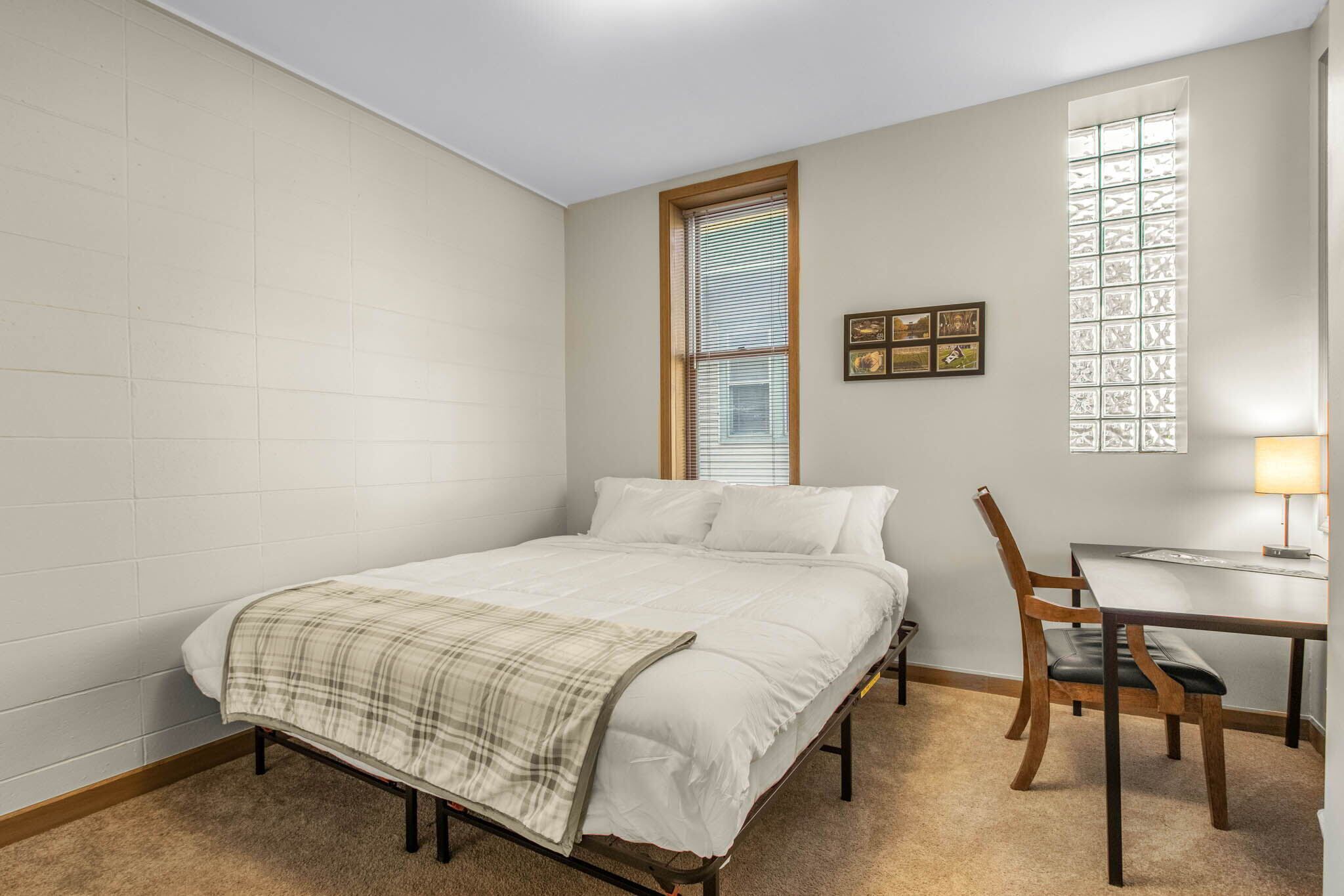 A bedroom with a bed, a desk, and a chair.