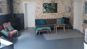 Un salon avec un mur en pierre, un canapé, une table basse et une cheminée.
