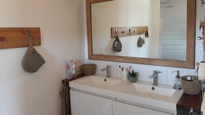 Une salle de bain avec un miroir encadré en bois, deux lavabos et un peignoir suspendu.