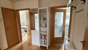 A spacious room with wooden flooring, a white bookshelf, and a small white table. - Quiet vacation apartment in the beautiful Sauerland (Meschede)