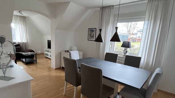 A modern, well-lit dining area with a large table and chairs, a white desk with a computer, and a view of the outdoors through large windows. - Quiet vacation apartment in the beautiful Sauerland (Meschede)