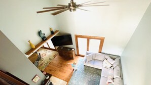 Un salon spacieux avec un grand canapé, une table basse en bois et un ventilateur de plafond.